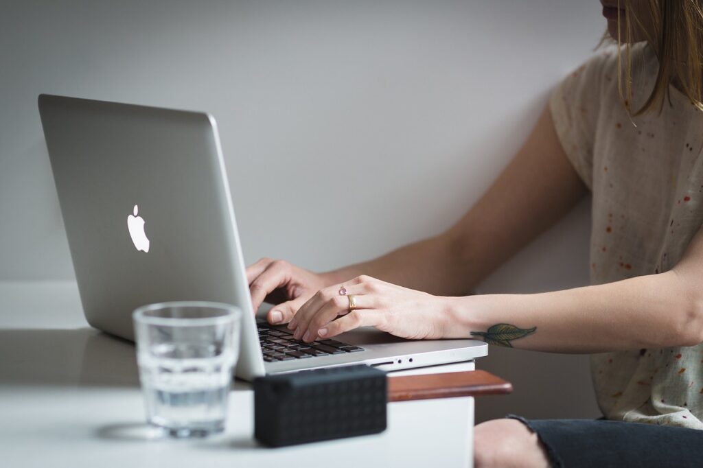 Girl sitting at a desk typing on a laptop computer. 