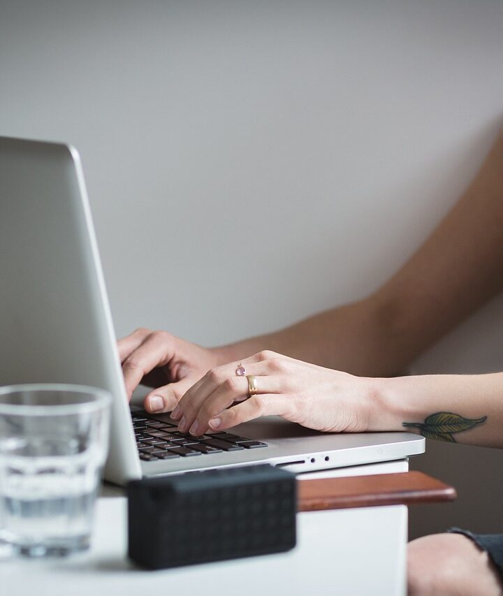 Girl sitting at desk typing on a laptop computer.